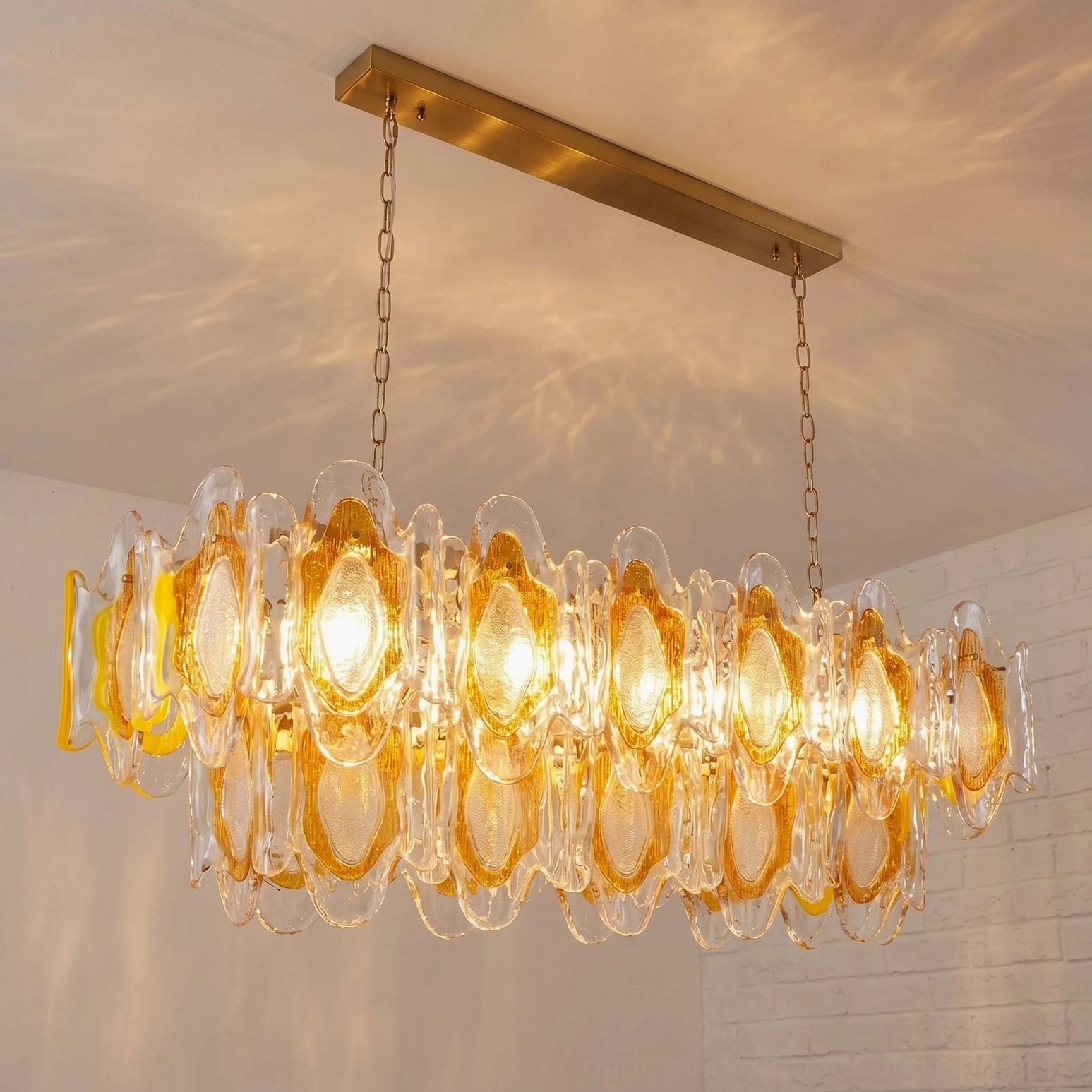 Side close-up detail of Marrina glass chandelier showing tiered sculpted glass petals and brass hardware against brick wall