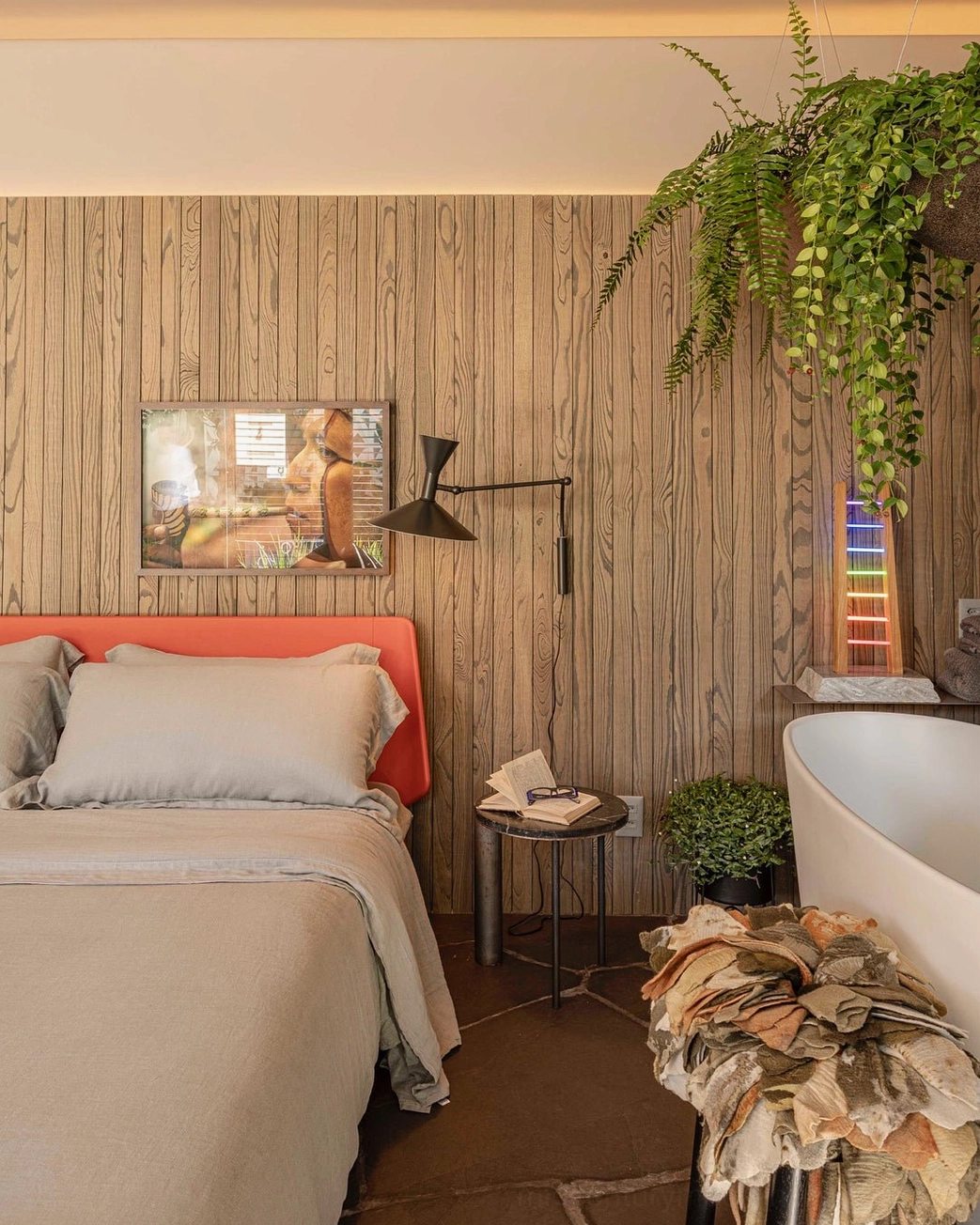 Compact black Marseille swing arm wall sconce in bedroom with wooden accent wall
