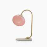 Marshmallow globe table lamp with brass gold frame and pink frosted glass shade on white marble base, front studio view