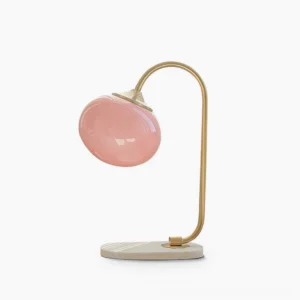 Marshmallow globe table lamp with brass gold frame and pink frosted glass shade on white marble base, front studio view