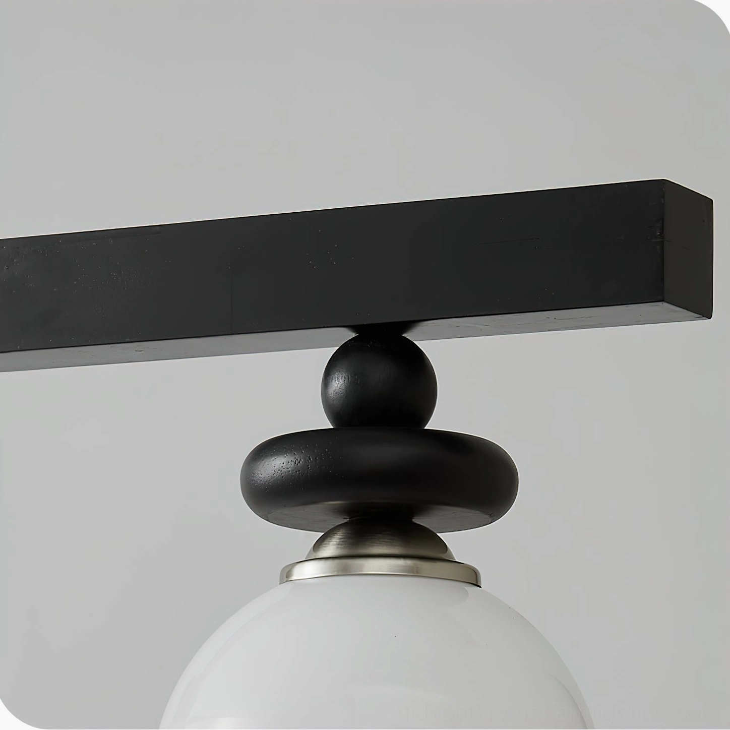 Macro close-up of Maru pendant light fixture showing stacked black metal components, silver trim details, and frosted glass globe