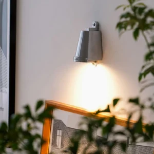 Mast wall spotlight illuminating gallery wall with framed art and botanical decor