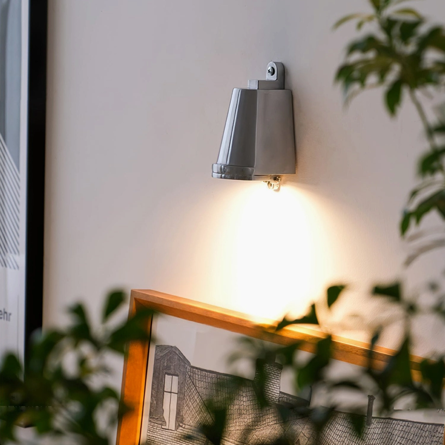 Mast wall spotlight illuminating gallery wall with framed art and botanical decor