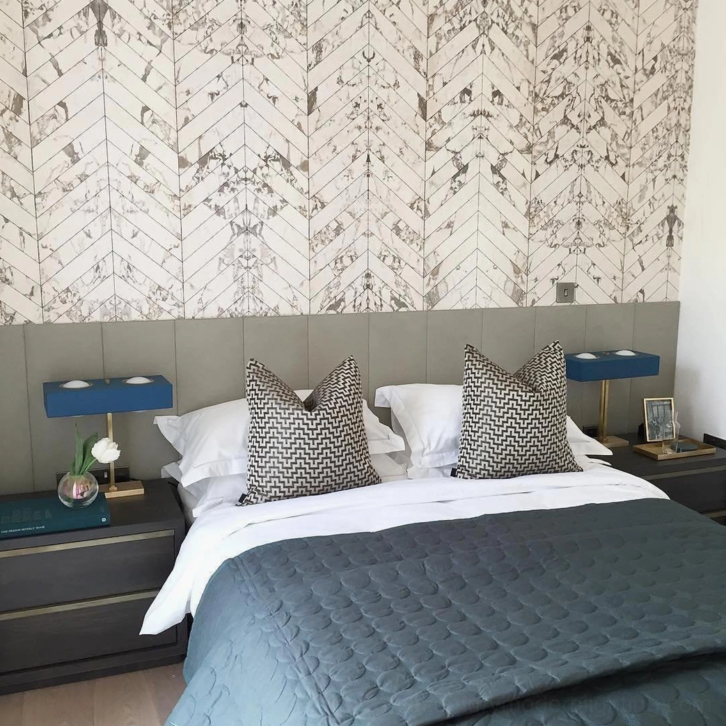 Pair of matching navy blue Kernel table lamps with brass hardware on master bedroom with geometric wallpaper