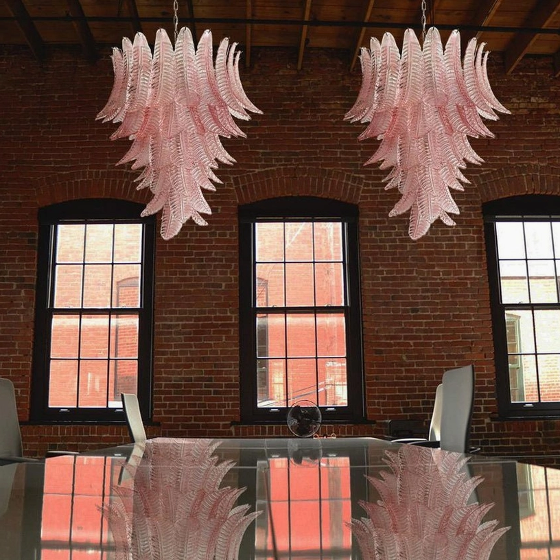 Two matching pink palm leaf Murano chandeliers overhead view in industrial brick dining room