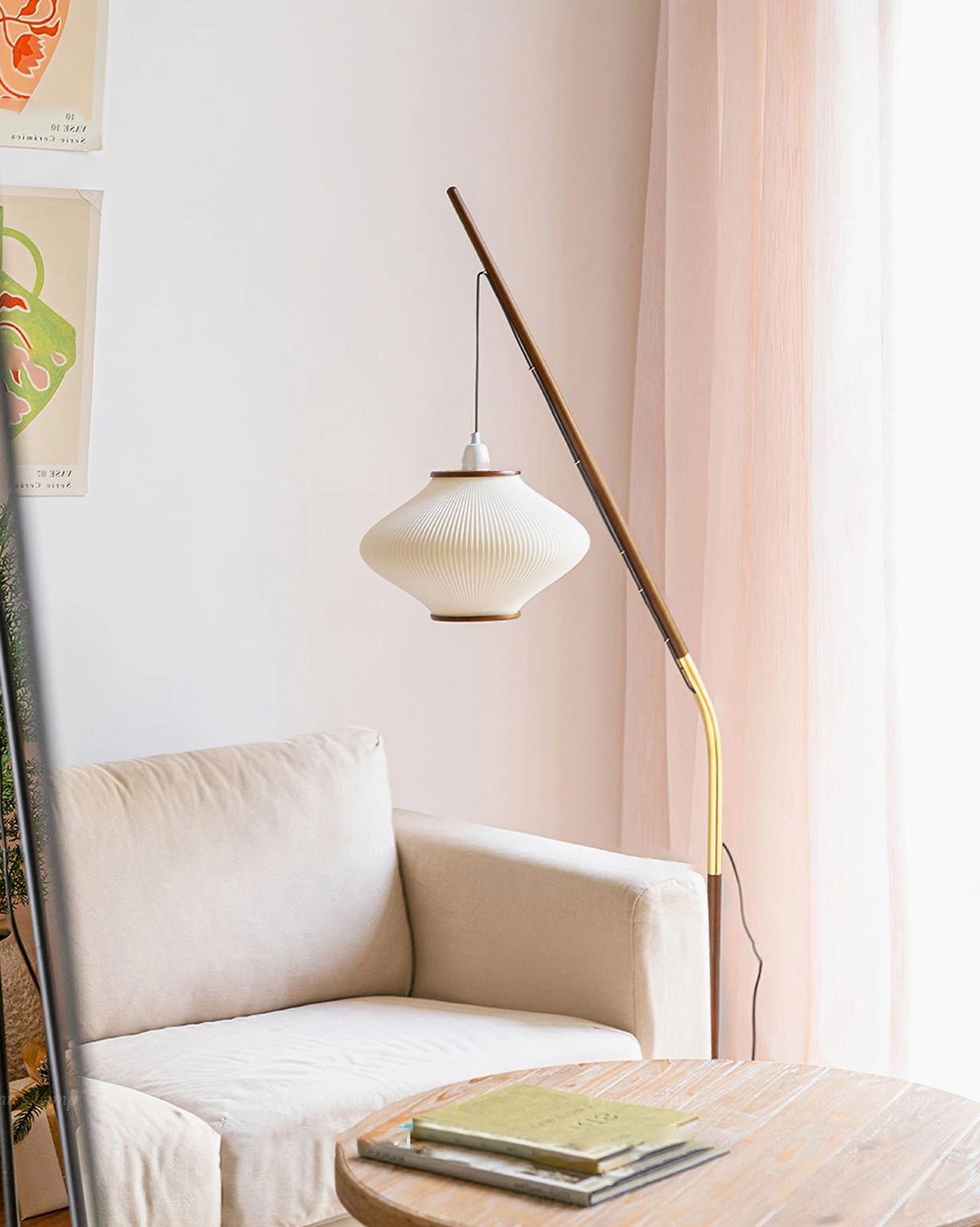 Matsusu arc floor lamp positioned in living room with stacked books and mid-century modern aesthetic