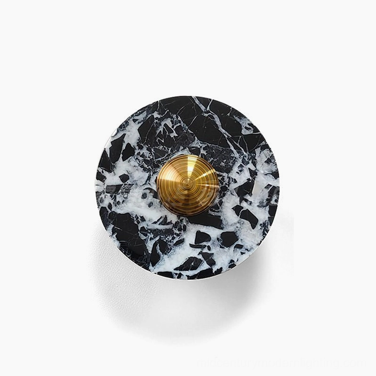 Medium size black marble wall lamp with white veining and brass accent hardware on interior wall