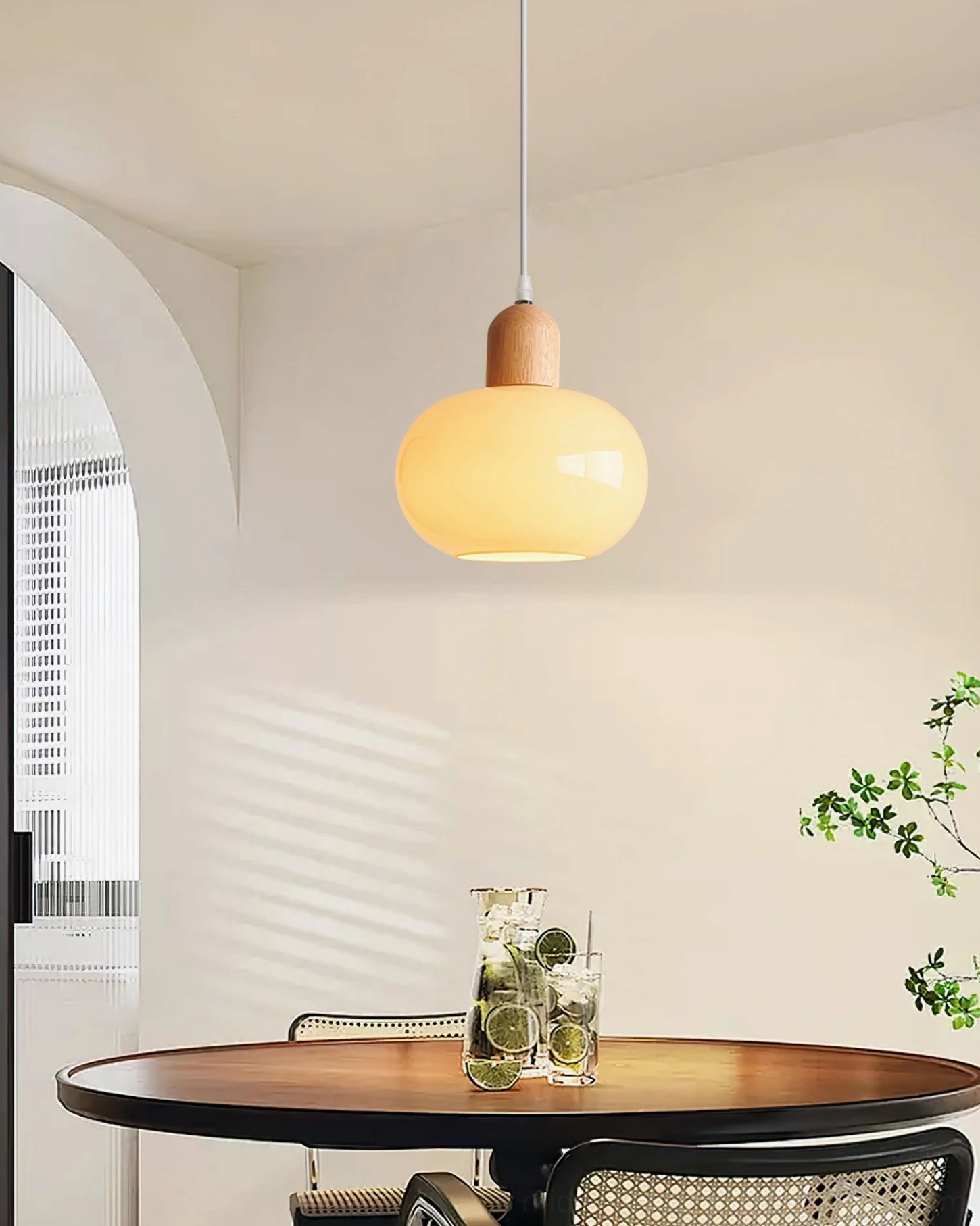 Single mellow cream glass pendant suspended above wooden dining table in Scandinavian interior, warm glow illuminating space