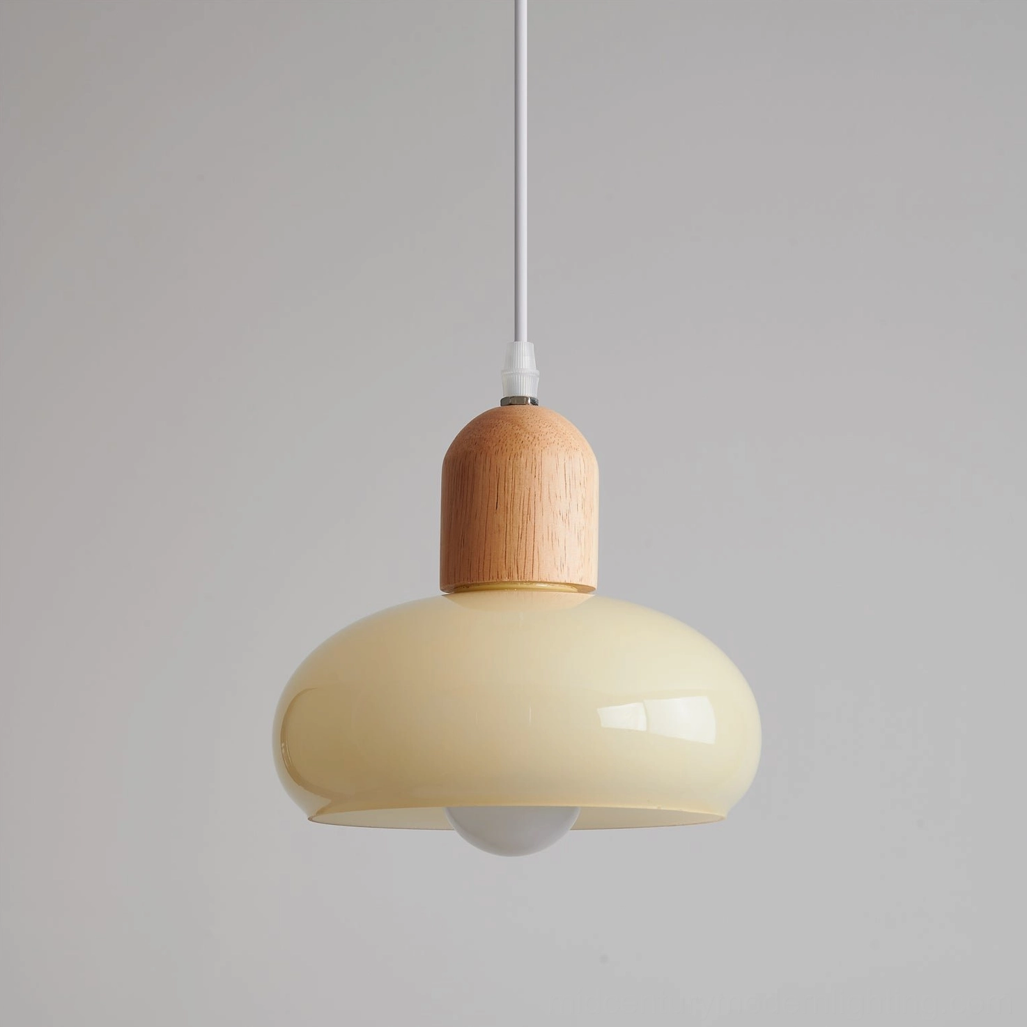 Close-up side profile of mellow pendant light featuring milk glass shade with exposed bulb socket and warm illumination
