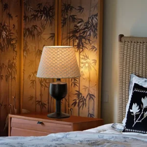 Mermaid mid-century modern table lamp in traditional bedroom setting with wooden nightstand and bamboo screen backdrop