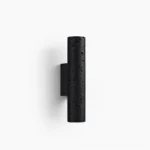 Meta cylindrical wall lamp front view, black matte travertine stone finish with porous texture on white background