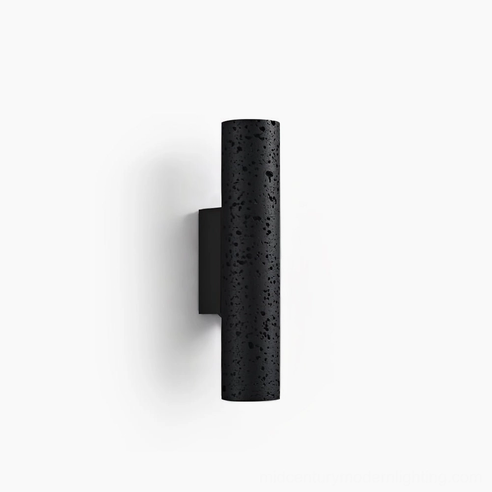 Meta cylindrical wall lamp front view, black matte travertine stone finish with porous texture on white background