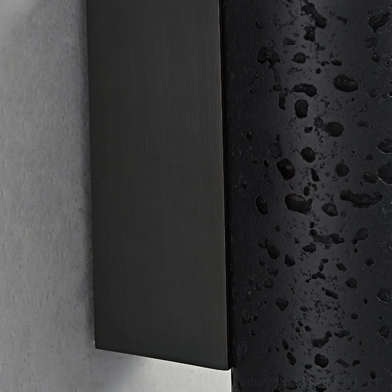 Close-up side view of Meta wall lamp mounting base and porous black travertine stone body texture