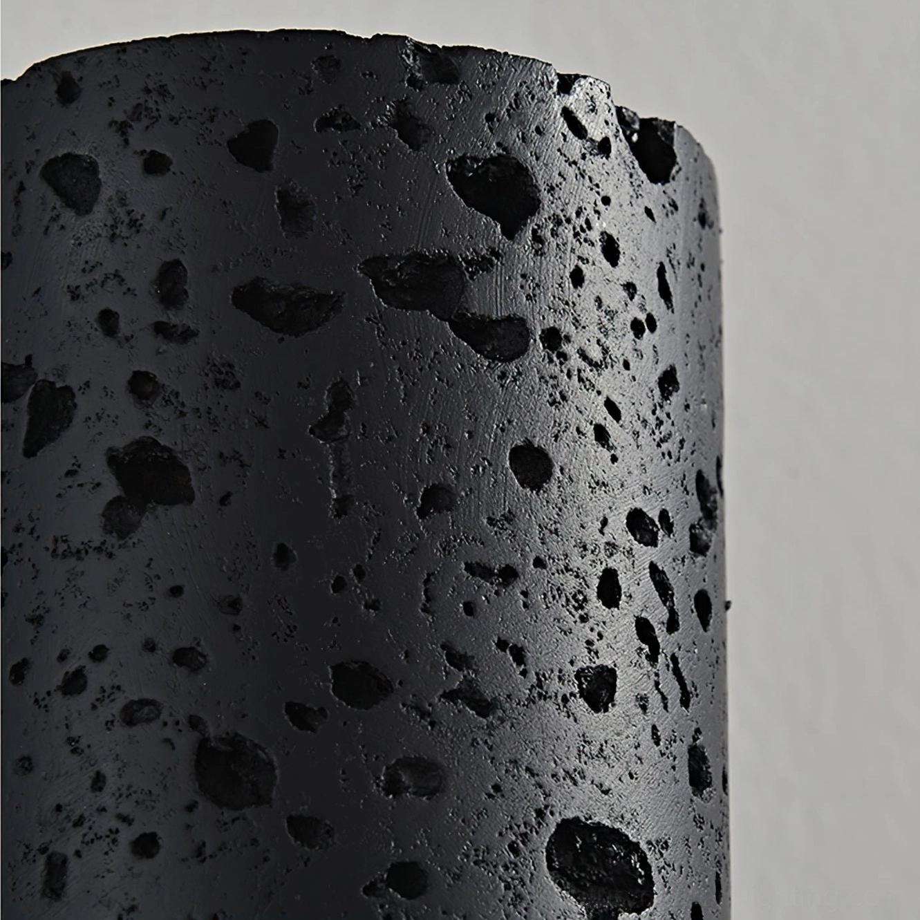 Macro close-up of Meta wall lamp travertine stone texture, dense black porous material detail