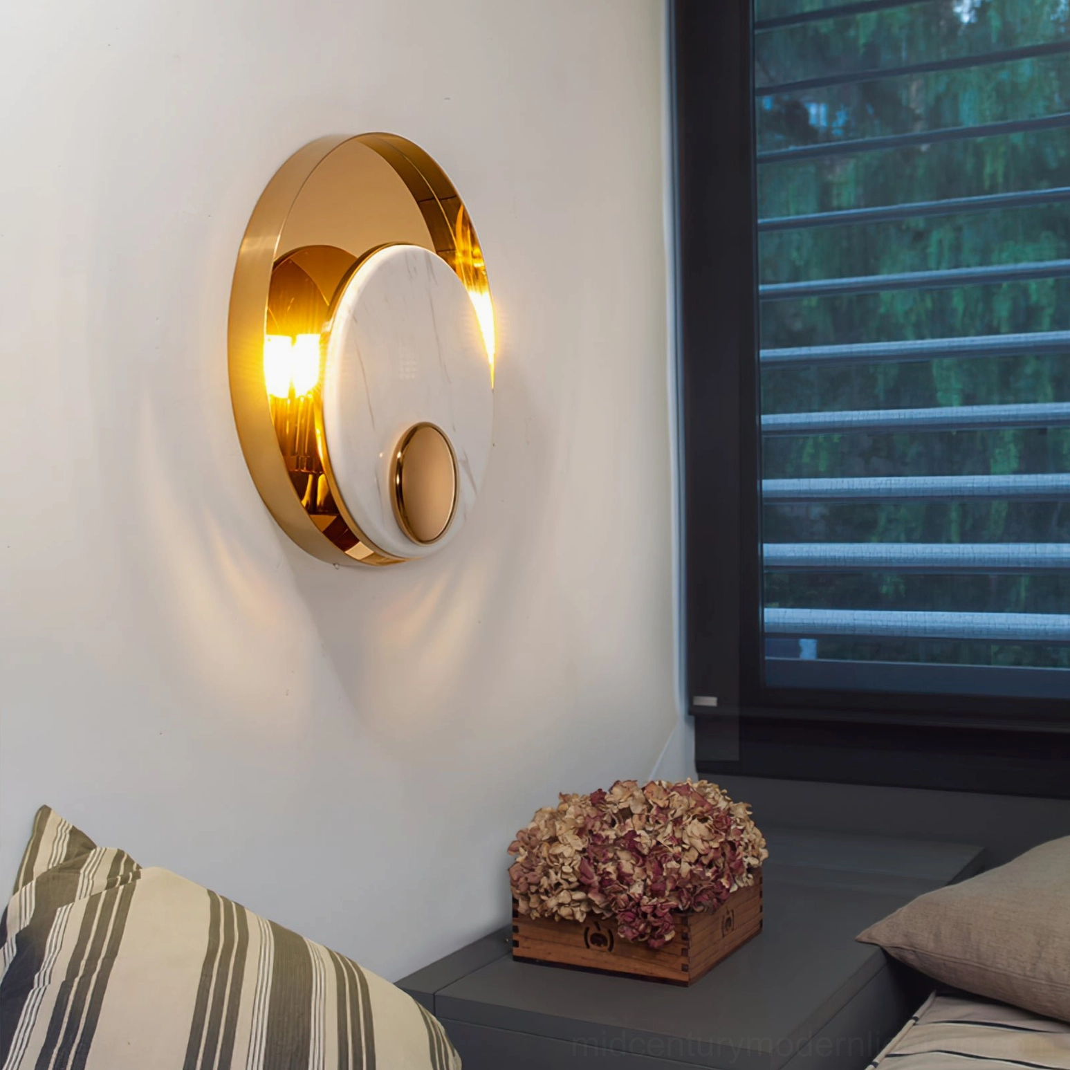 Illuminated white marble wall sconce with gold trim creating warm ambient light in modern bedroom bedside setting