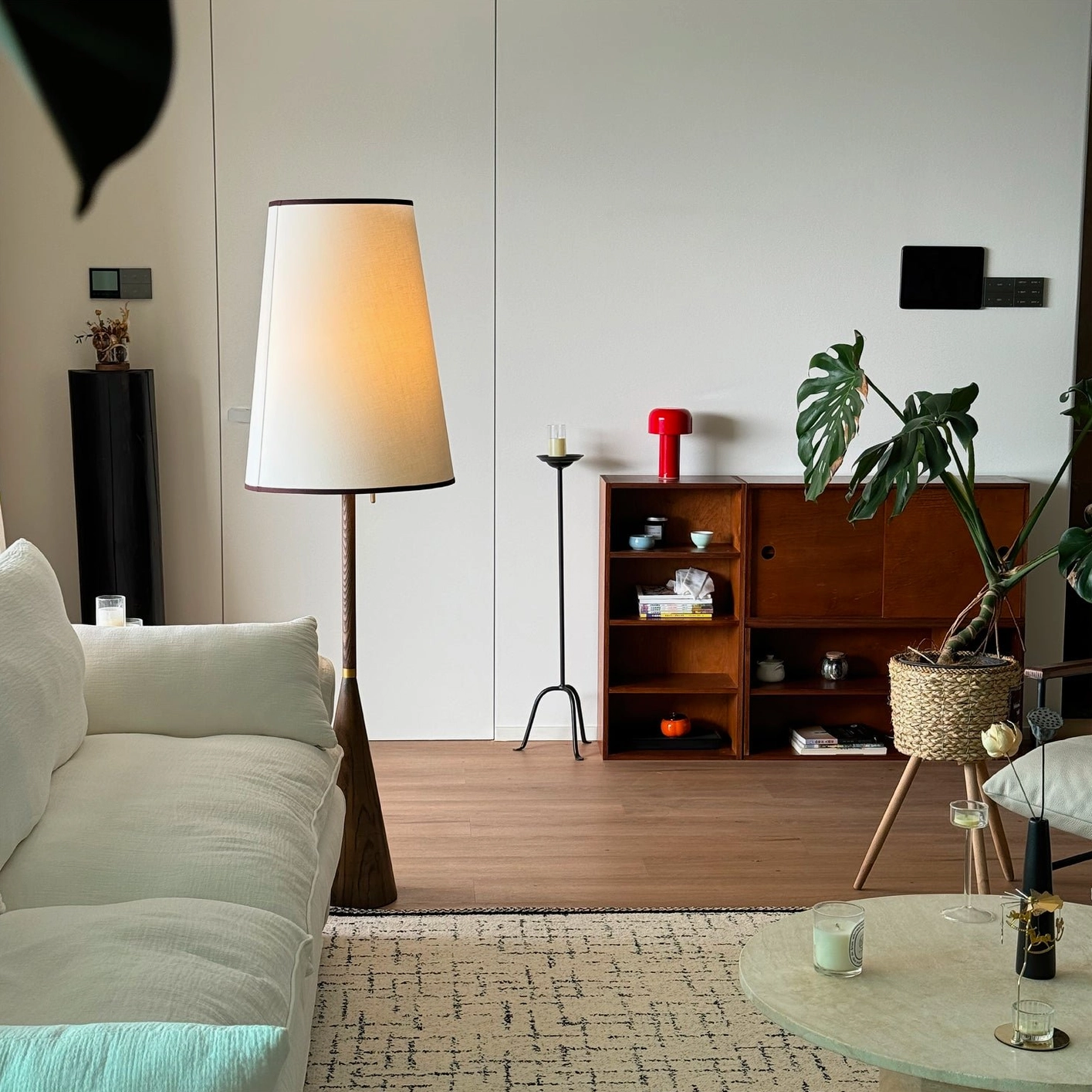 Mezzo tapered wood floor lamp in mid-century modern living space with white sofa and green plant