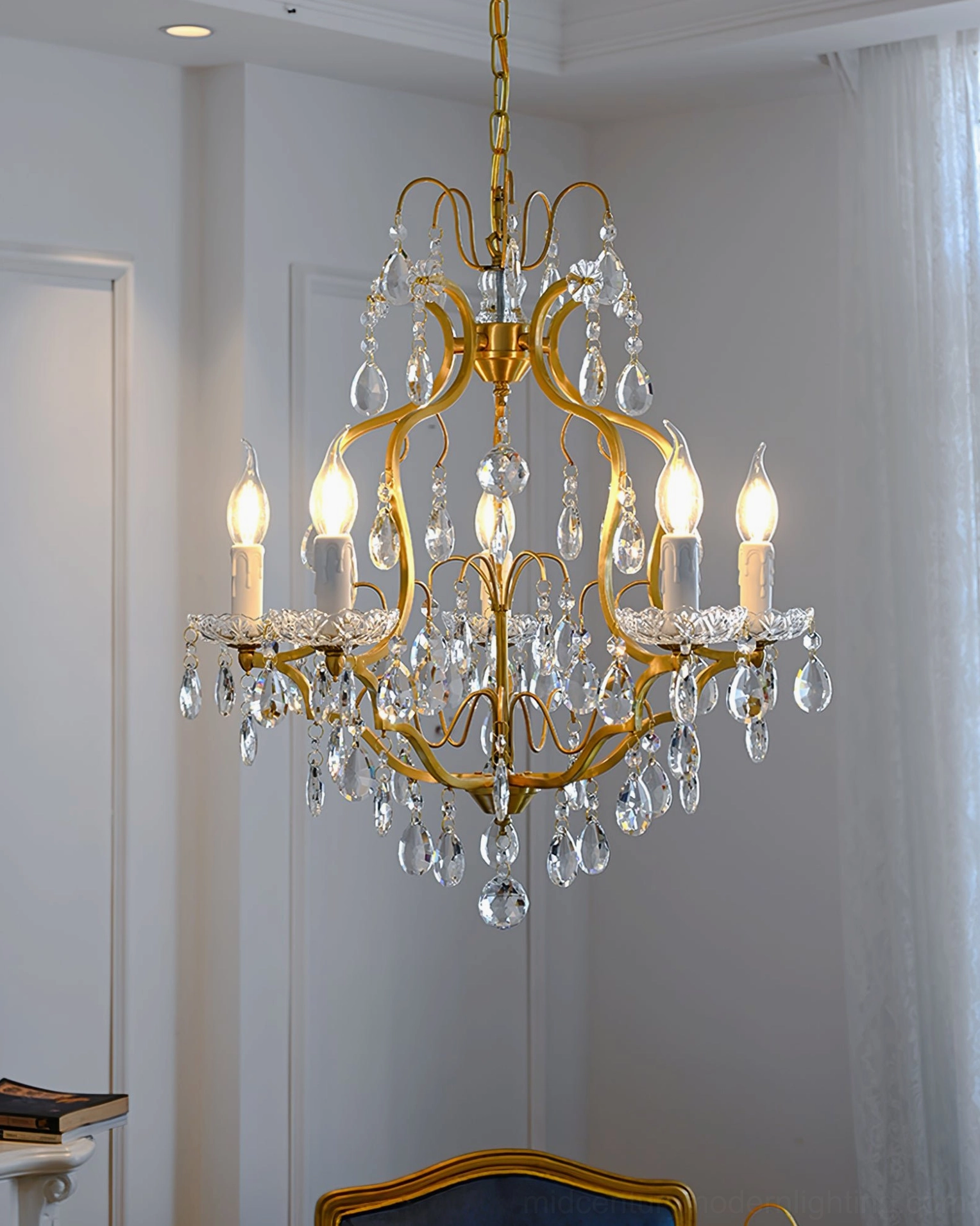 Symmetric brass frame chandelier with clear crystal droplets in minimalist white bedroom