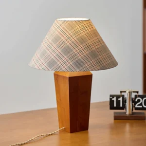 Cabin table lamp on home office wooden desk, three-quarter angle showing brown wood base with checkered lampshade