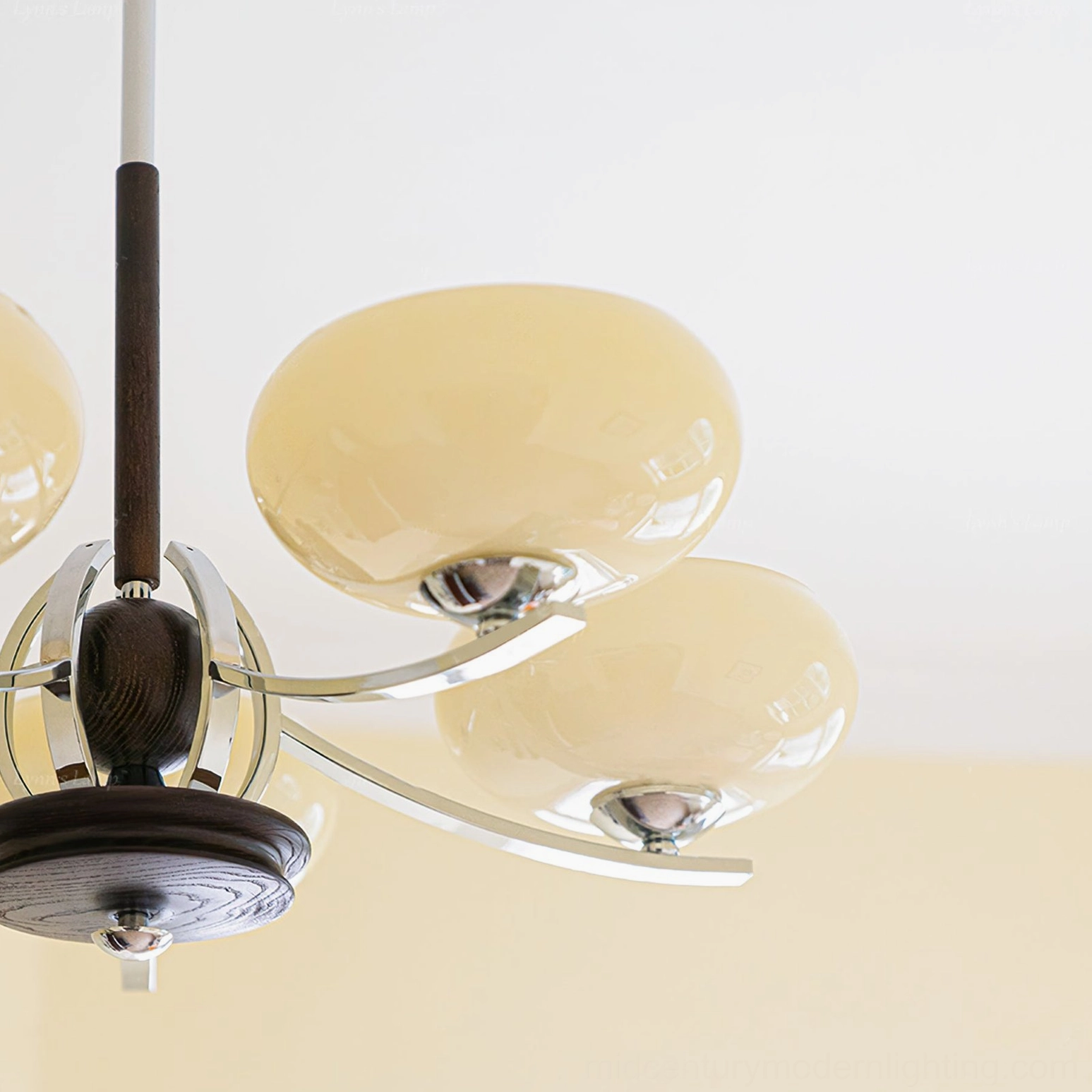Close-up overhead view of mid-century modern chandelier assembly showing polished chrome details, dark wood grain, and glossy cream glass shades