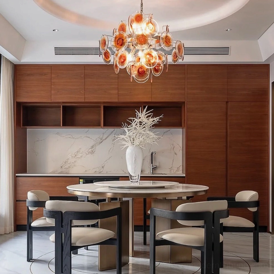 Amber glass disc chandelier installed in modern luxury dining room creating warm ambient lighting