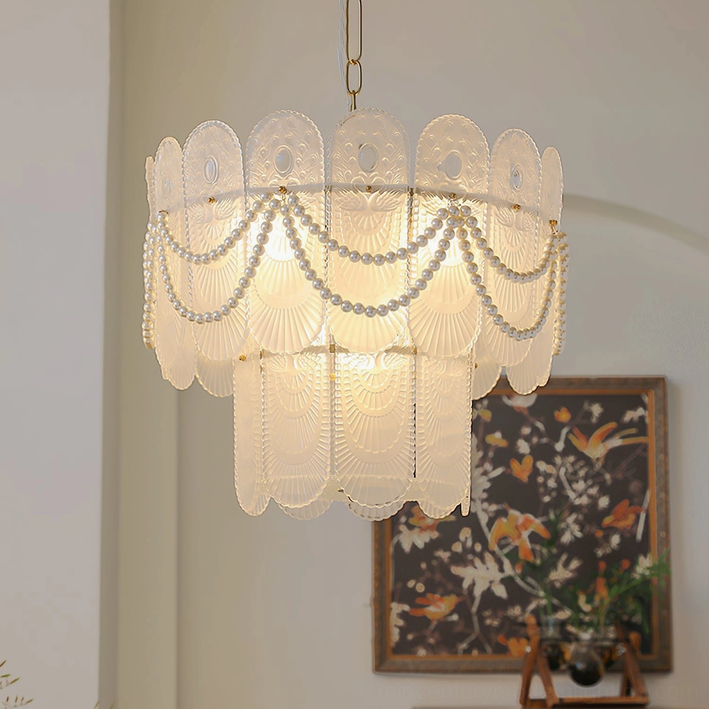 Mid-century modern two-tier glass chandelier with copper or white metal frame, three-quarter angle showing embossed glass detailing and warm illuminated light