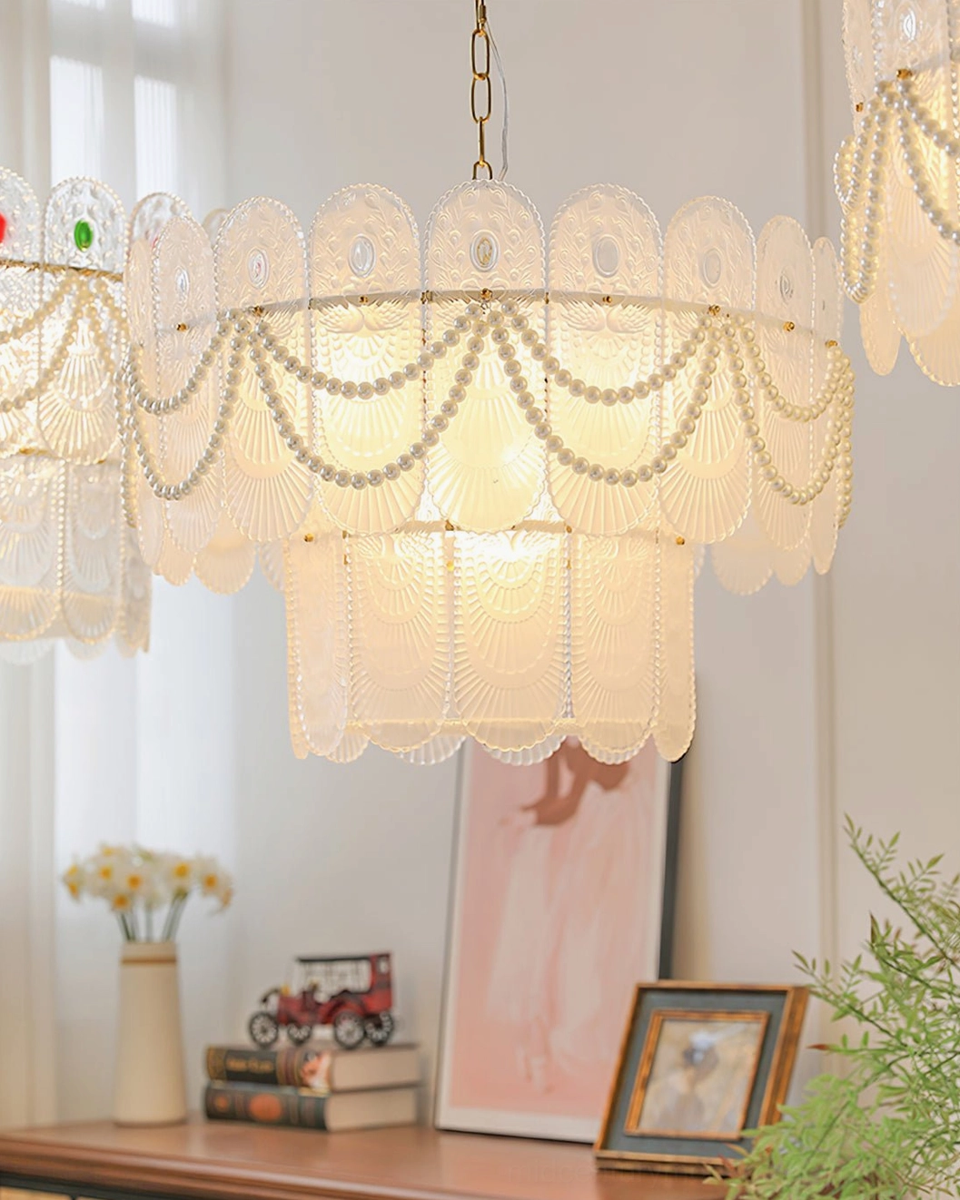 Two-tier scalloped glass chandelier in bright home study environment with desk, window curtains, and decorative accessories, front three-quarter angle
