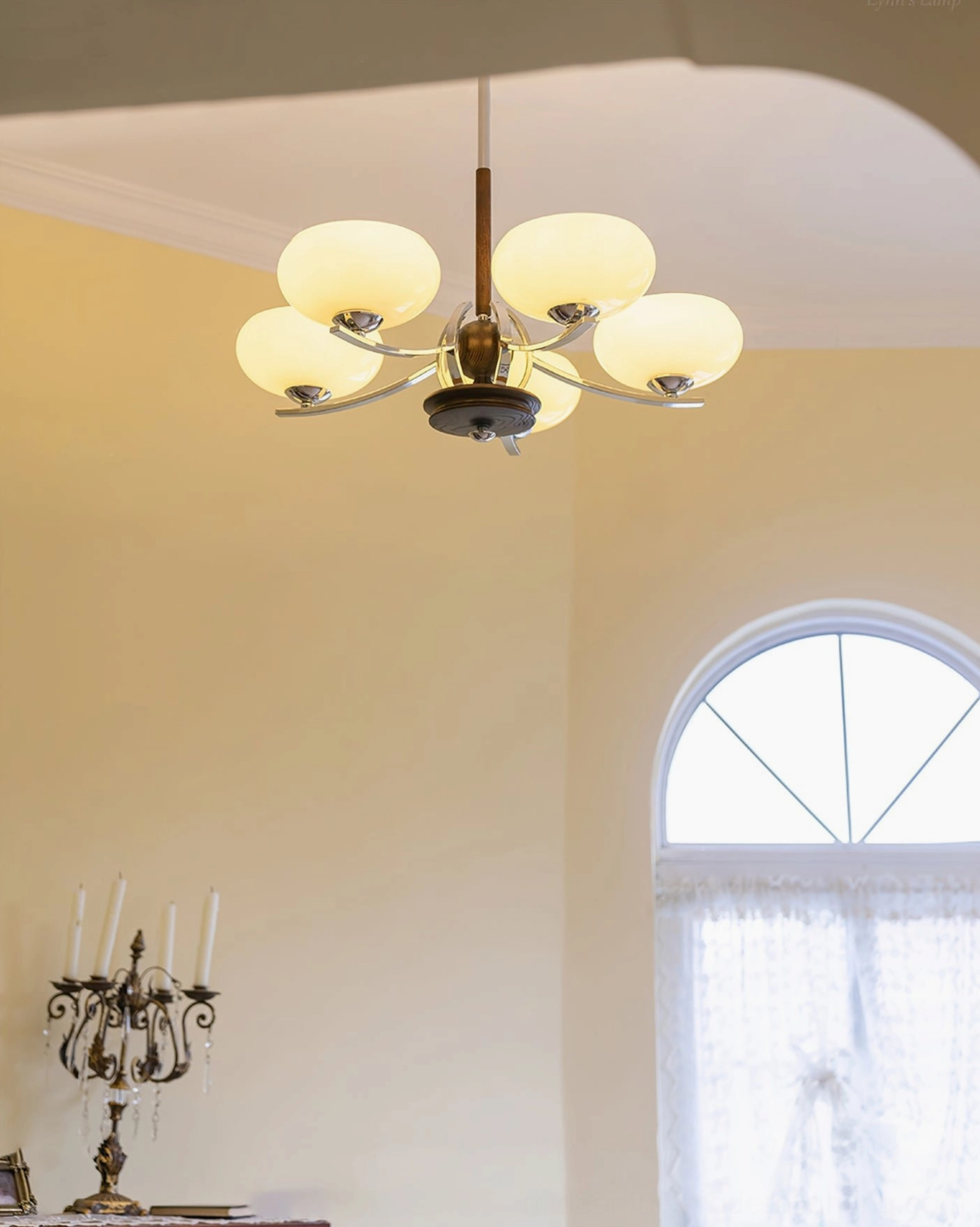 Six-light mid-century glass chandelier with cream rounded shades, dark wood frame and chrome hardware in arched window interior space