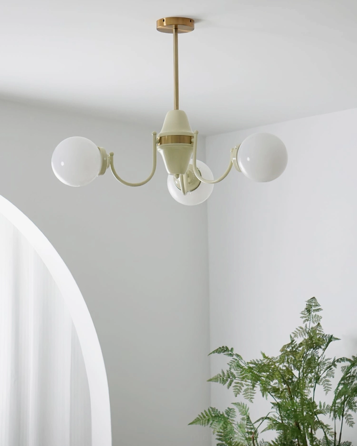 Compact four-head globe chandelier side angle view in minimalist white room with arched curtain