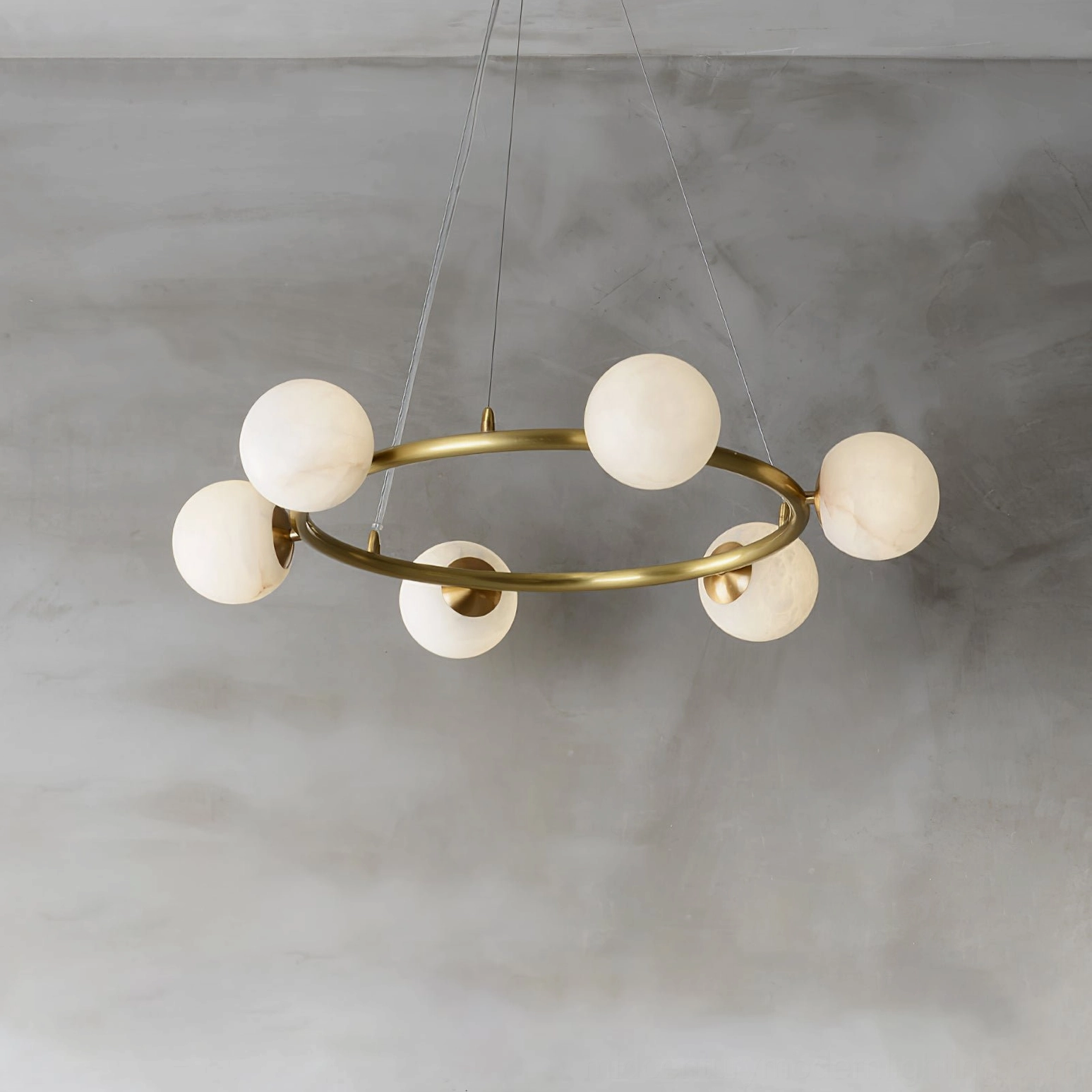 Mid-century modern ring pendant chandelier with geometric brass frame and veined alabaster globes, oblique side overhead angle