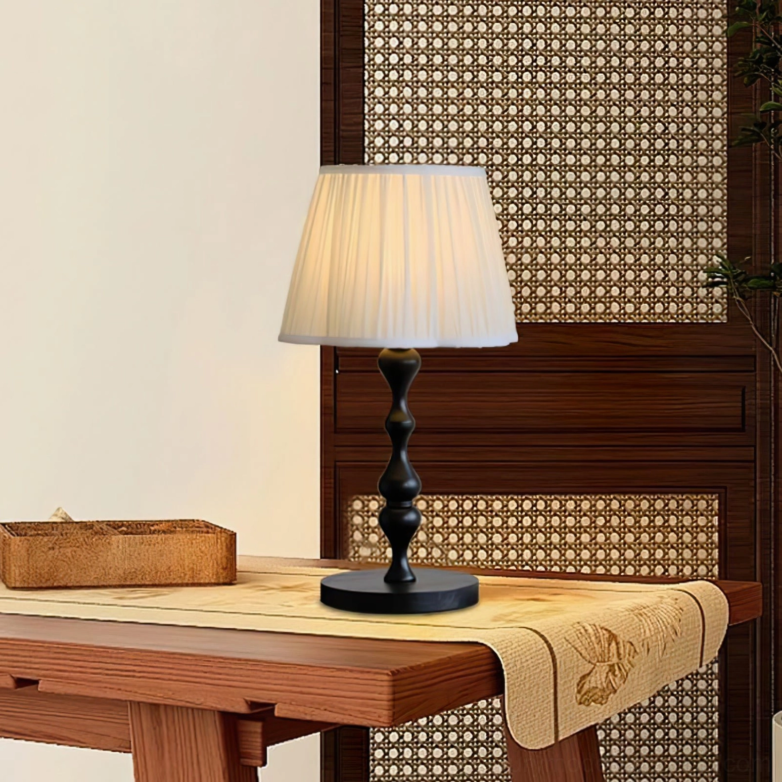 Contemporary pleated shade table lamp lit on wooden table with rattan panel, warm ambient lighting in modern interior