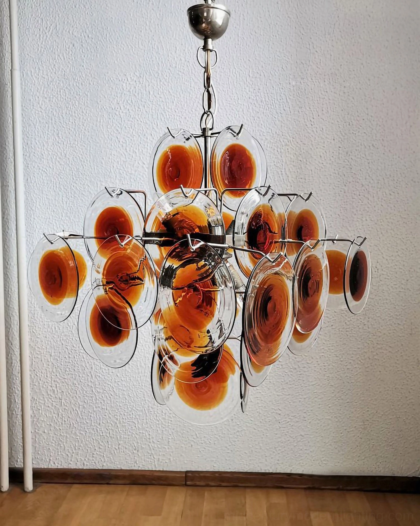 Mid-century modern glass disc chandelier with chrome frame in contemporary wooden floor interior