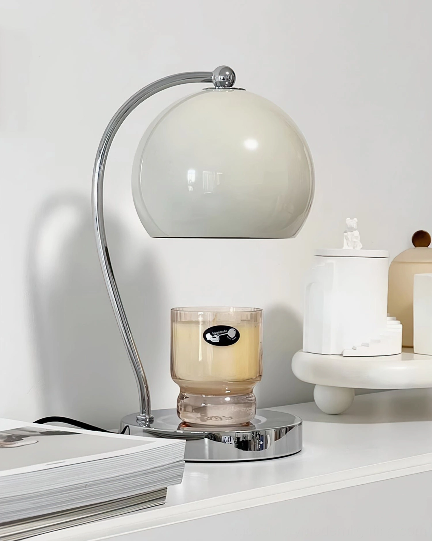Chrome metal base globe lamp positioned on bedroom dresser with decorative home accessories