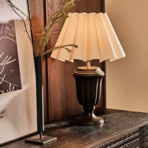 Mid-century modern Tisdale table lamp displaying warm ambient lighting on vintage wooden dresser with decorative items