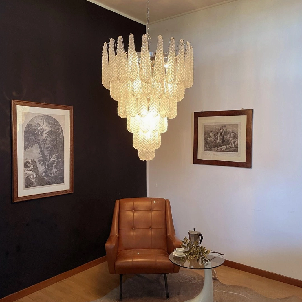 Mid-century modern tiered Murano glass chandelier casting warm light in contemporary living room with leather armchair and retro design elements
