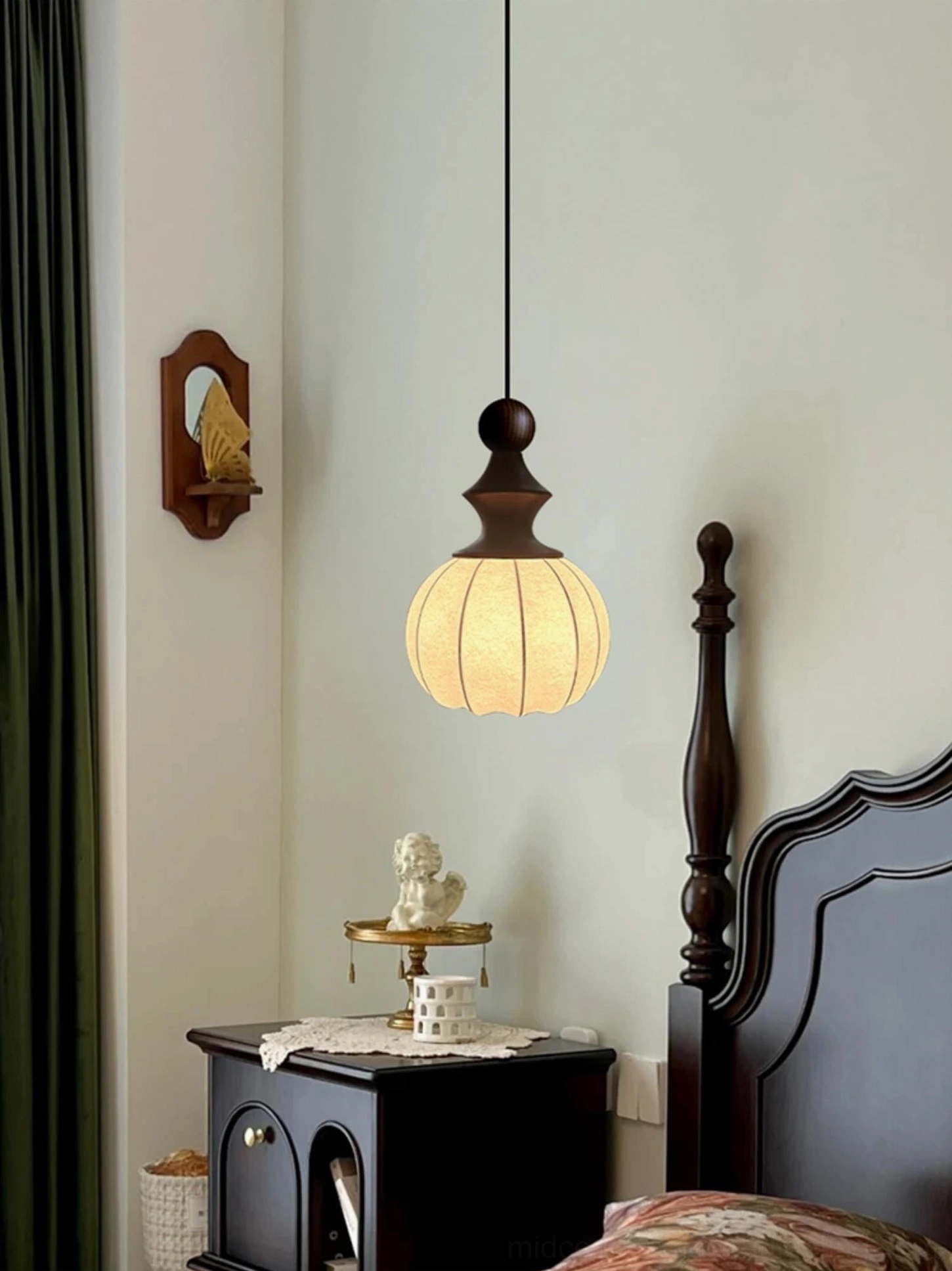 Mid-century modern pendant fixture showing soft warm glow illuminating ribbed fabric shade and turned wooden base above bedside table