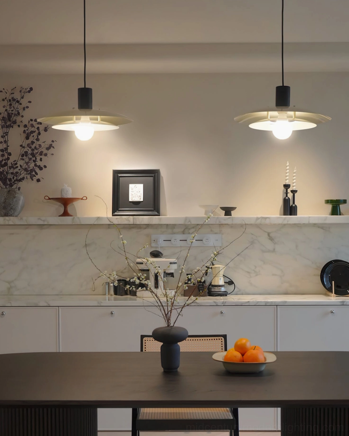 Pair of mid-century pendant lamps in dark wood dining space connected to kitchen with tabletop decor