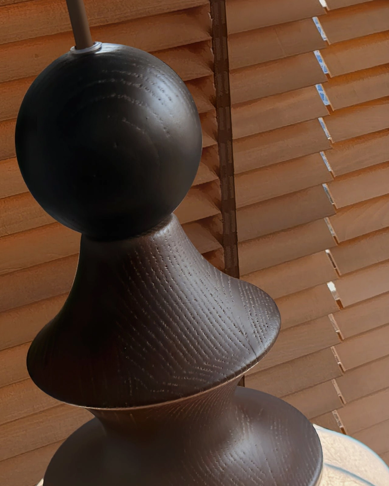 Close-up detail of turned solid walnut wood base of mid-century modern pendant light showing natural wood grain and craftsmanship