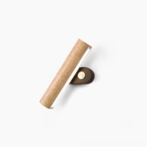 Mid-century modern rotatable tube wall lamp in natural wood finish, studio overhead view with minimalist white background