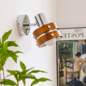 Mid-century modern wall sconce with warm LED lighting in Scandinavian interior setting with plants