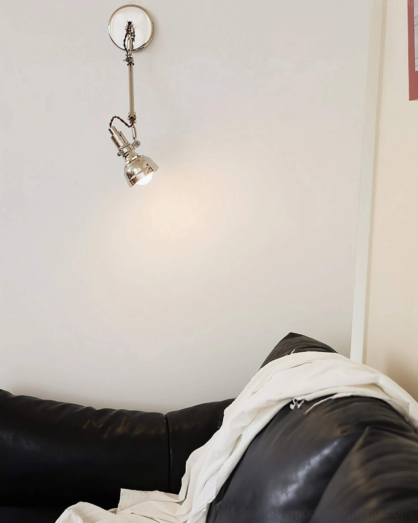 Low frontal view of articulated swing arm wall lamp in living room sofa setting, warm ambient glow