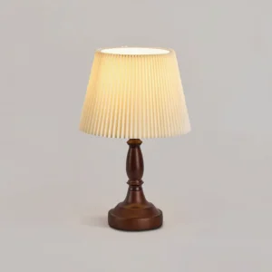 Walnut wood table lamp with glowing pleated shade showing warm ambient lighting quality