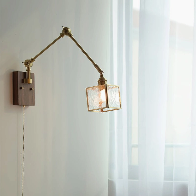 Three-quarter view of mid-century wall lamp with dark wood base, brass articulated arm, and frosted square glass shade in contemporary setting
