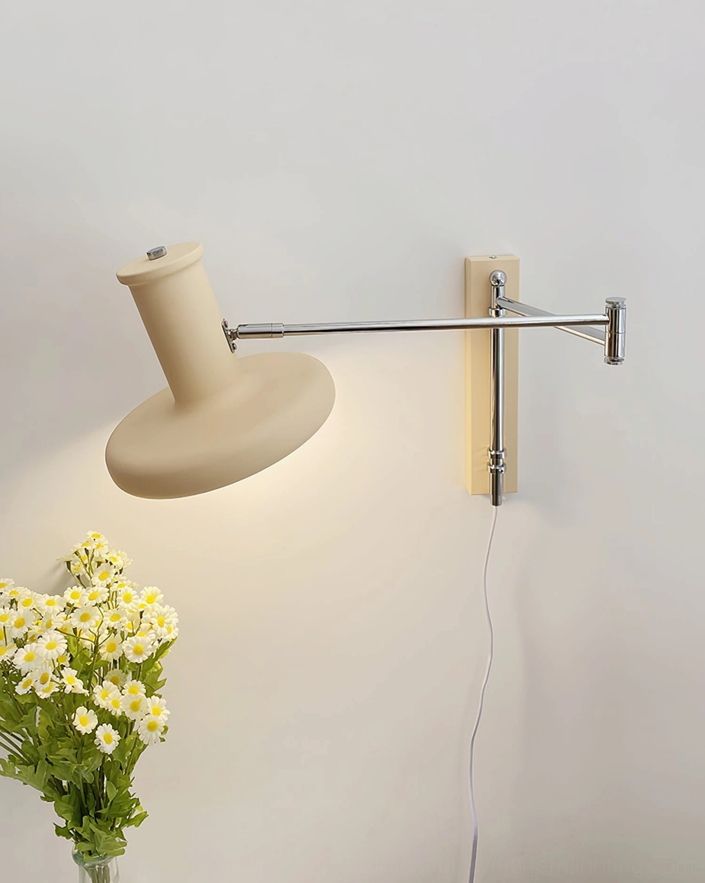 Angled side view of cream-colored swing arm wall sconce with matte finish and adjustable articulated arm against plain wall
