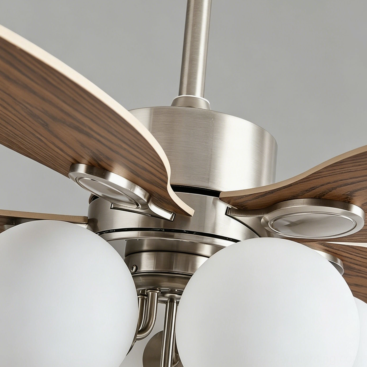 Angled studio view of mid-century ceiling fan light with frosted glass globes illuminated, showcasing walnut and chrome material contrast and geometric design