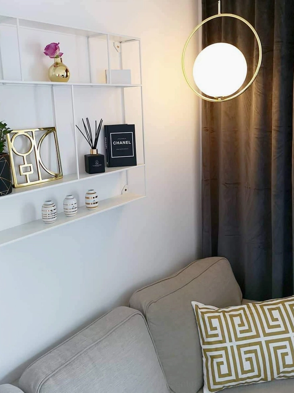 Single Mila circular hand-blown glass pendant in modern living room with decorative wall shelves, contemporary lighting design statement