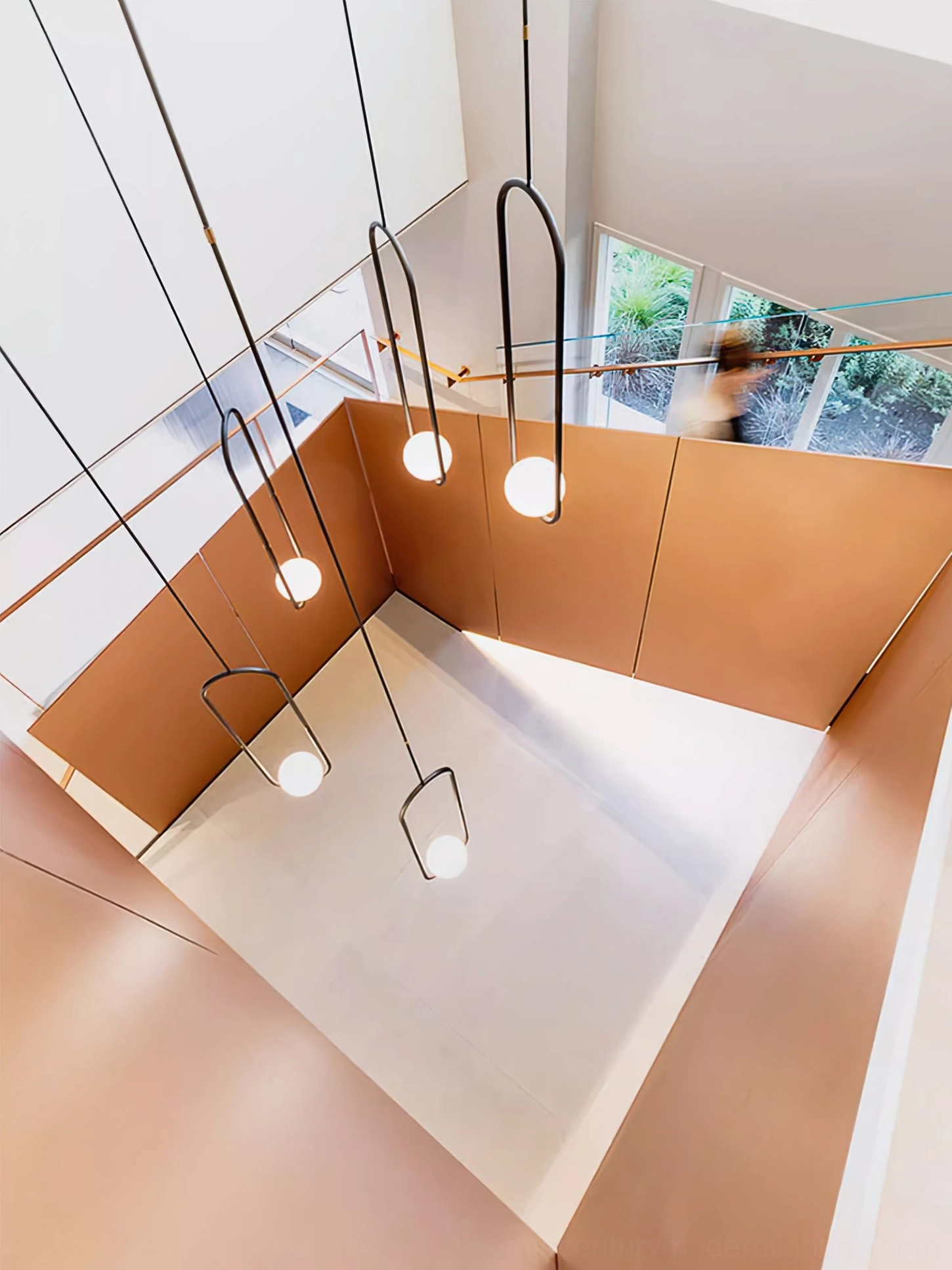 Overhead bird's-eye view of Mila pendant lamp set installed in modern duplex atrium with black frames and copper accents