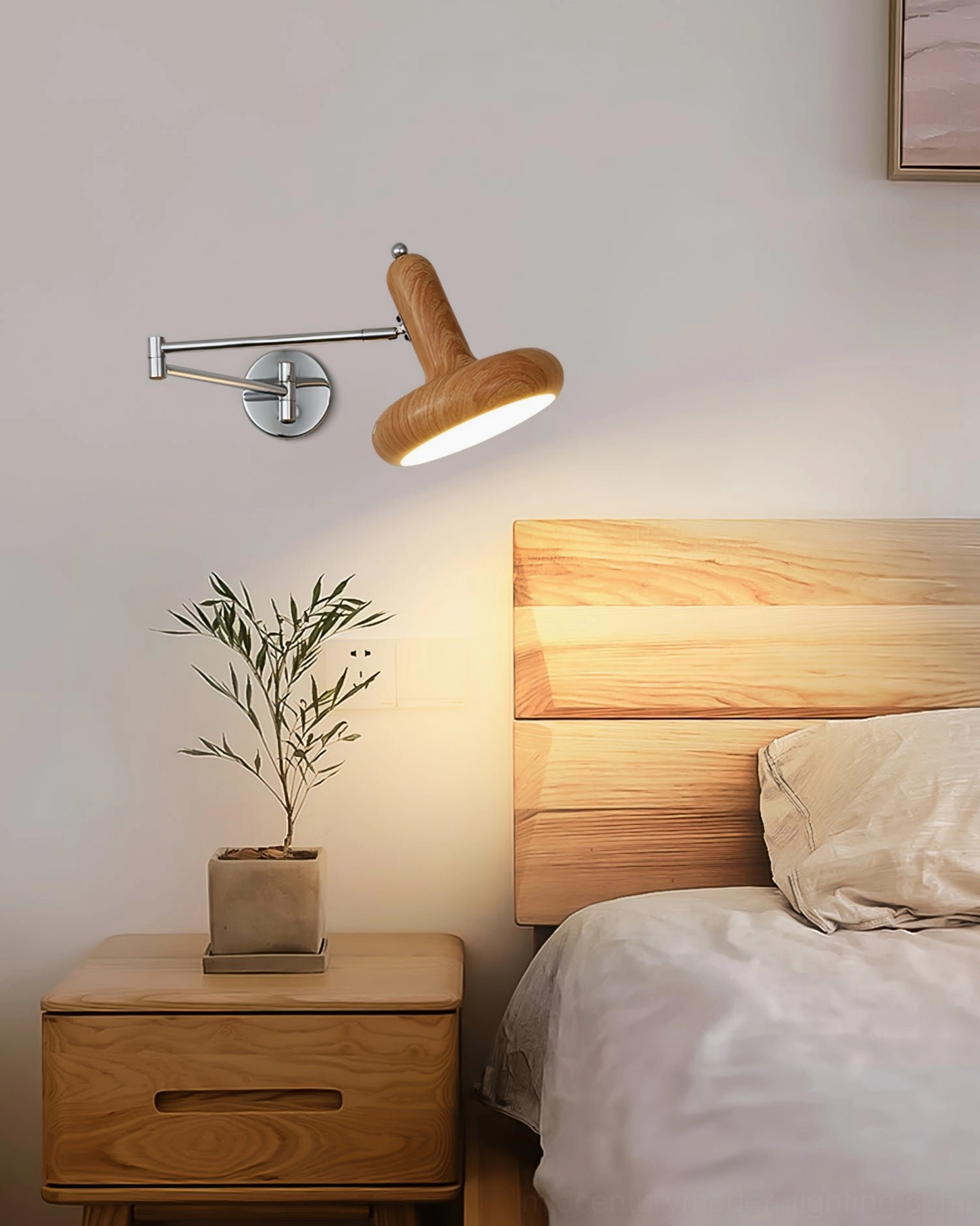Milena swing arm wall lamp with light oak wood finish installed above modern light wood headboard, side view