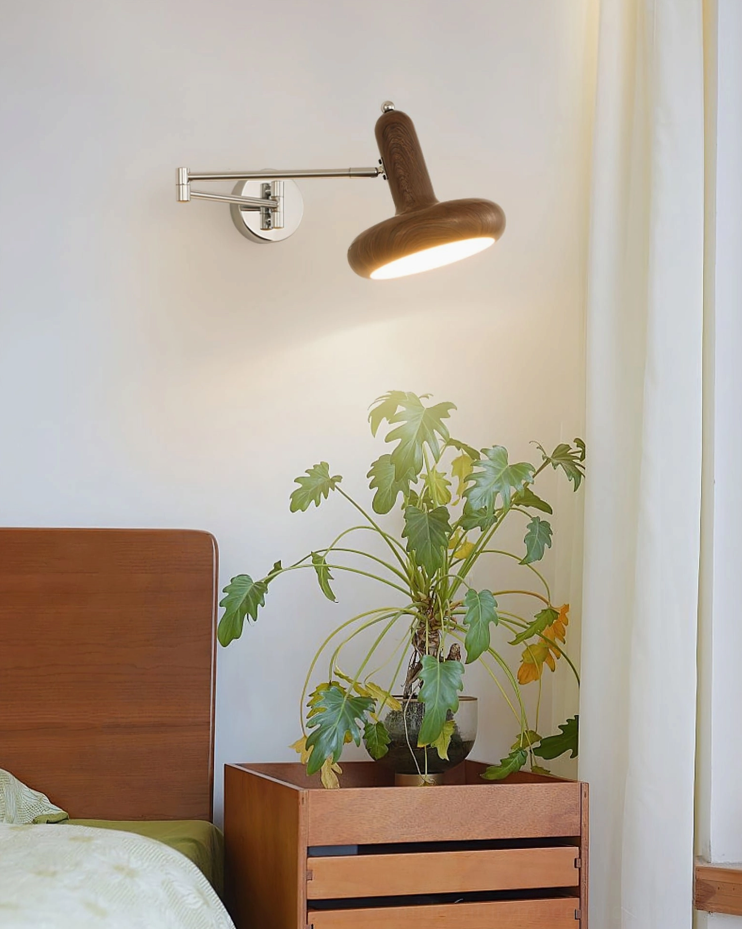 Milena adjustable wall sconce with natural wood finish mounted in Japandi minimalist bedroom with potted plant and wooden furniture