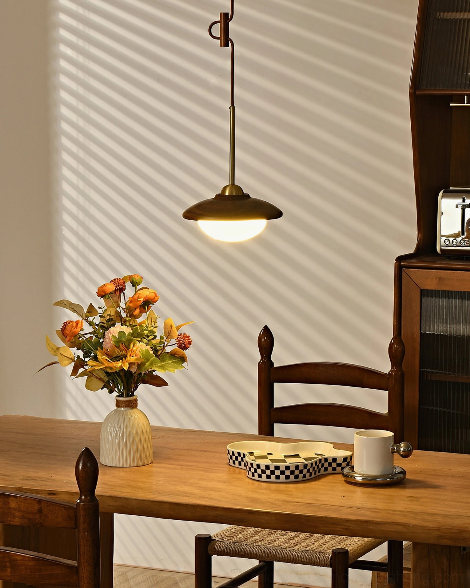 Milivia single pendant light illuminated over dining table - front view detail