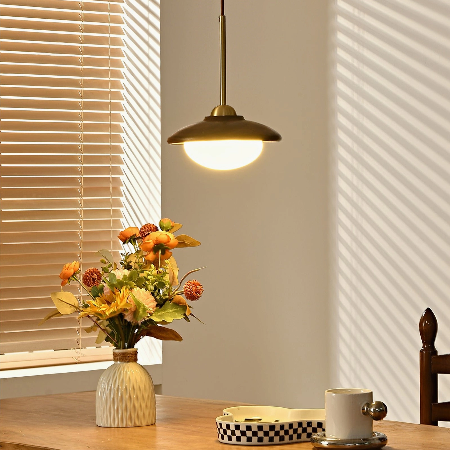 Vintage-inspired Milivia pendant light over dining area with wooden blinds - warm brass detail